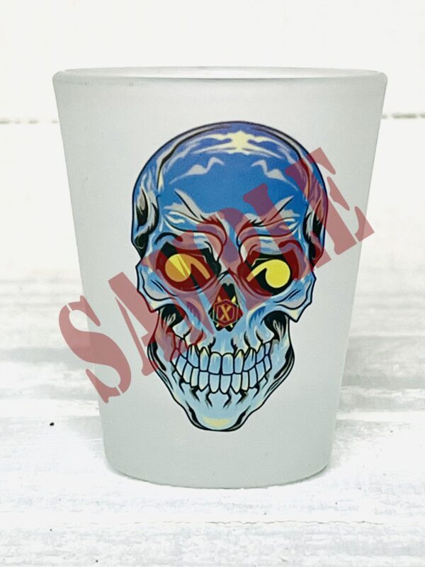 A frosted shot glass with a skull on it.